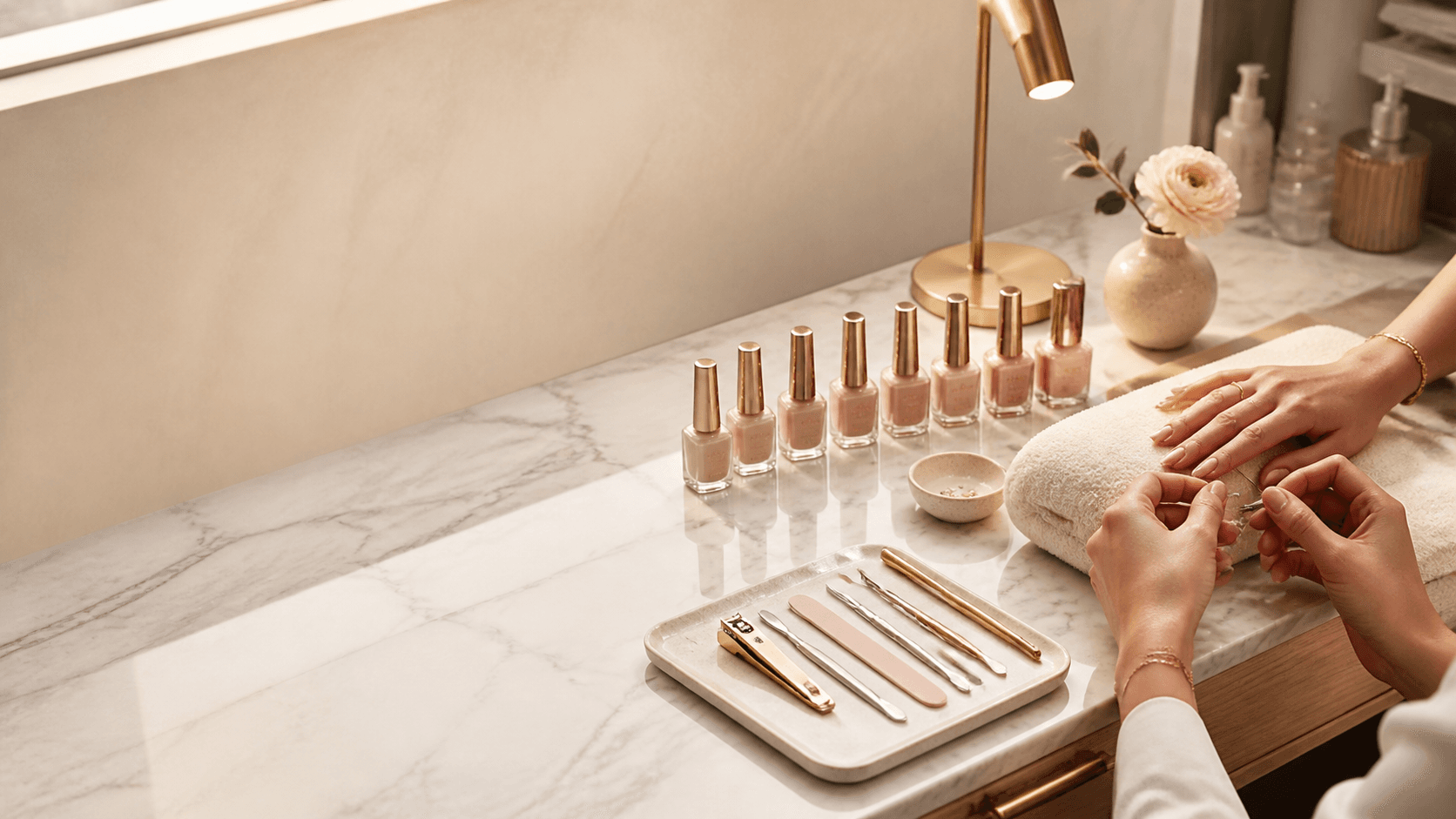 Boutique-Nagelstudio mit Marmorfläche, Polituren in Rosé- und Champagnertönen und Designerin bei der Arbeit